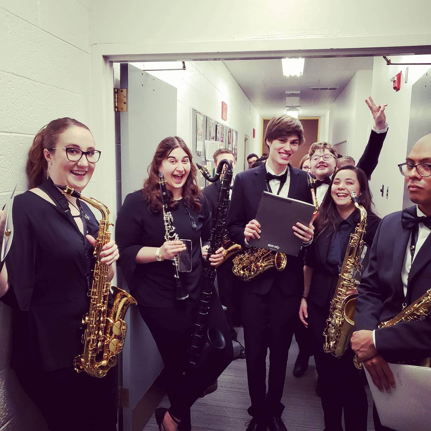 Smiling Saxophone and Clarinet Ensemble students after a concert in the hallway