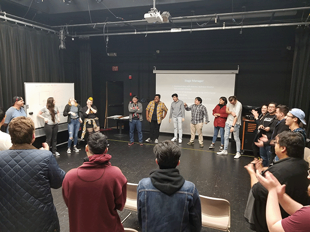 Theatre students standing on stage with building materials