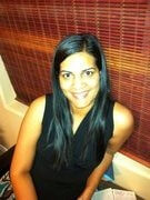 Rashmi Menon sitting against a window smiling