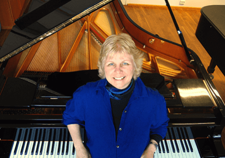 Anne Kilstofte smiling in front of a piano.