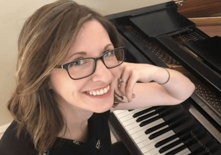 Annie Taylor smiling while leaning on her piano.