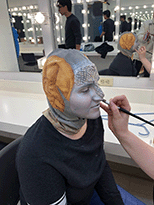 Stage makeup being applied to turn student into mythical creature