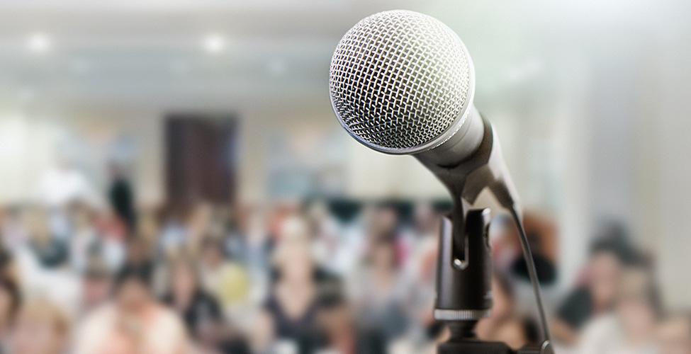 Microphone in front of a crowded room.