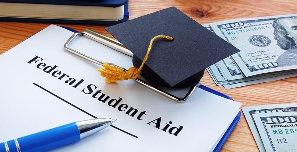 Federal student aid papers and small graduation cap.