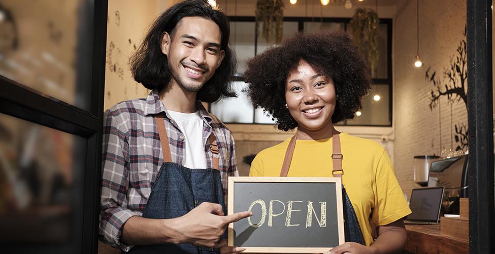 Small business owners holding an open sign