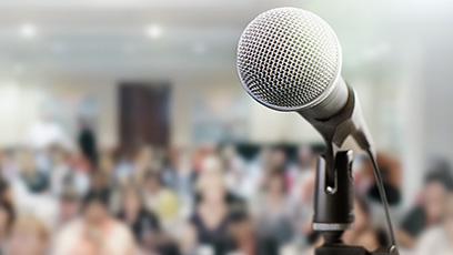 Microphone in front of a crowded room.