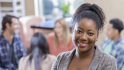 An African American woman stands confidently in front of her support group.