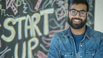 An entrepreneur standing in front of a black board with the words "start up"