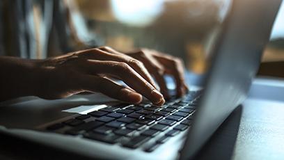 Hands typing on a laptop