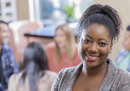 An African American woman stands confidently in front of her support group.