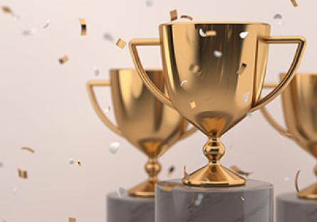 Three gold trophies with falling gold confetti
