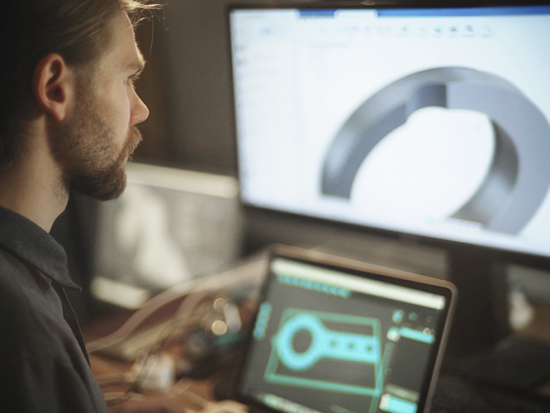 Male student working at a wide computer screen with CAD 3D imaging software