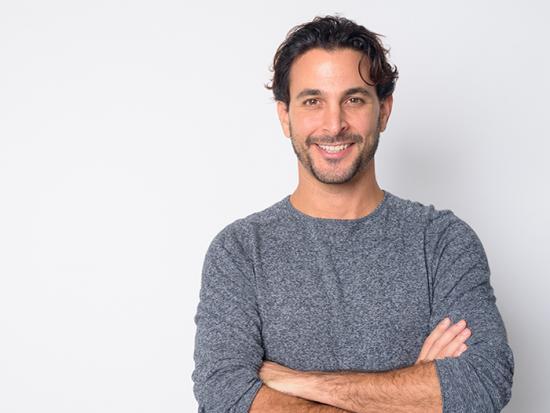 Student smiling for camera with his arms crossed