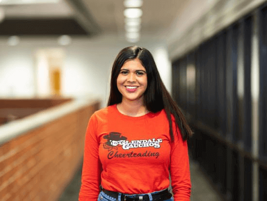 Smiling student in hallway wearing a GCC Cheerleading shirt