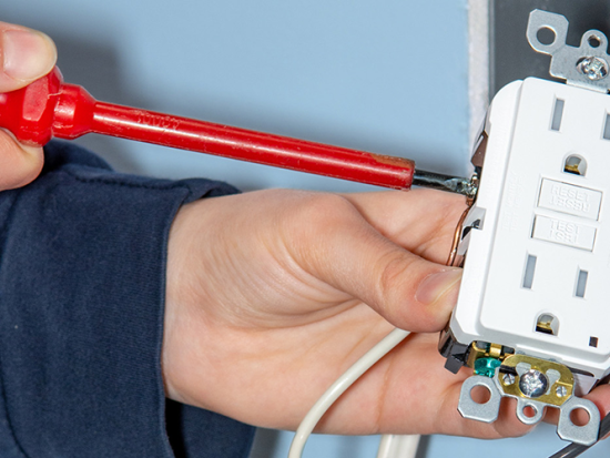 An electrician testing an electrical outlet.