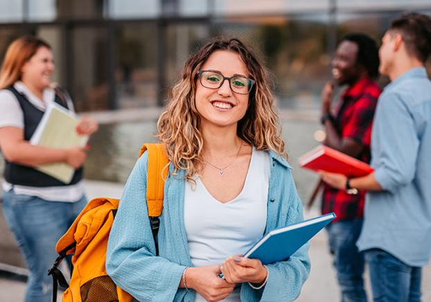 Smiling female student wearing glasses and a yellow backpack