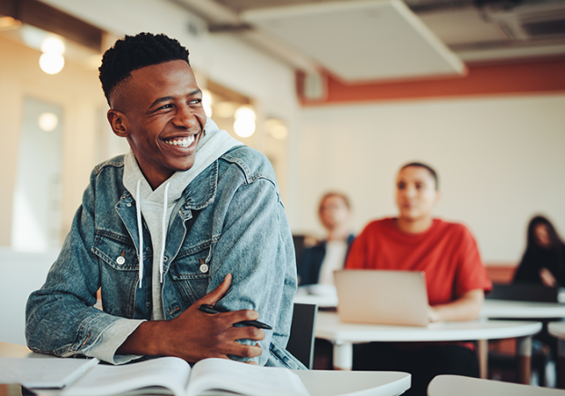 Smiling male student sitting in a classroom.
