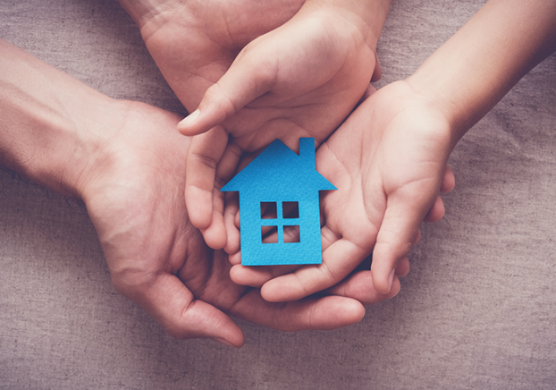 Adult and child hands holding paper house.