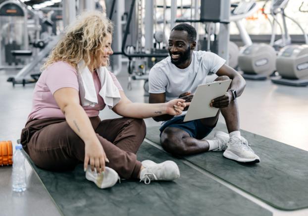 A picture of two people in a gym having a conversation.