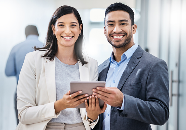 Two businesspeople standing together and holding a digital tablet in an office.