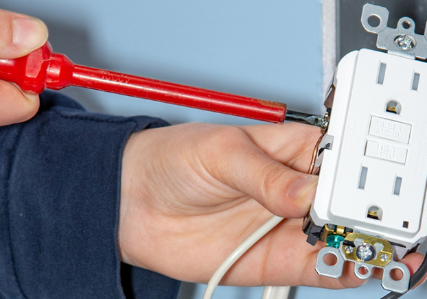 An electrician testing an electrical outlet.