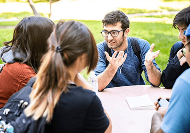 Group of students having a discussion around a table.